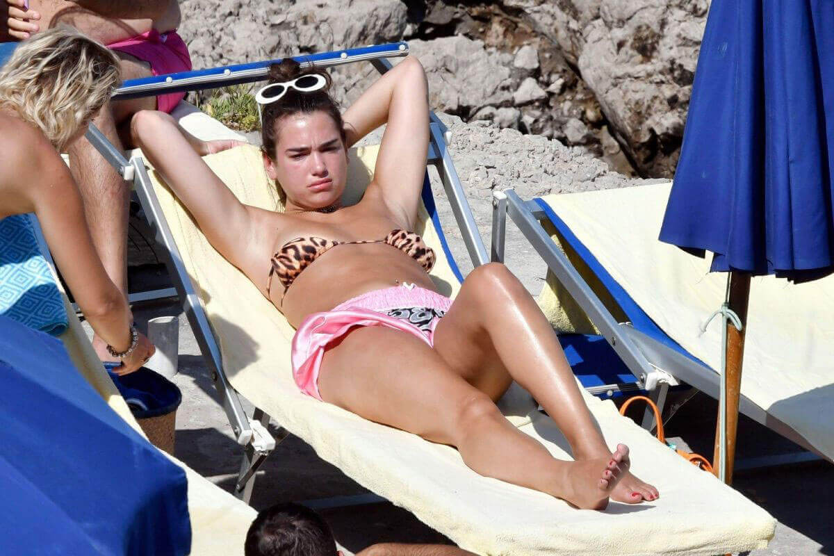 Dua Lipa Sunbathing at a Beach in Capri Photos