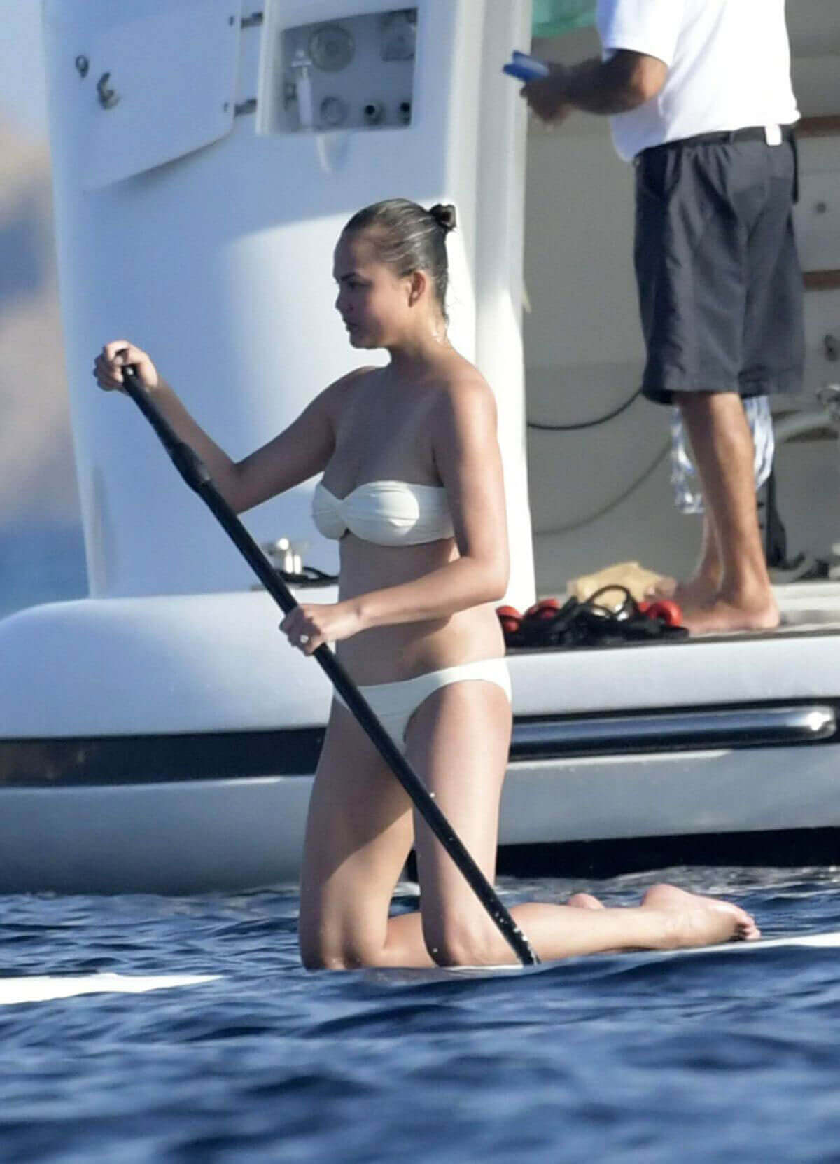 Chrissy Teigen wears white bikini at Paddleboarding in Sardinia