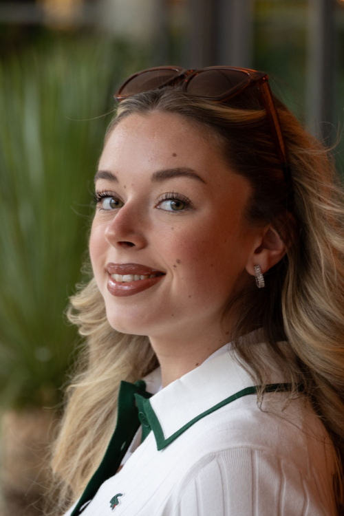 Close-up of Emma Broyon elegant hairstyle and Lacoste white polo with green collar detail at Roland Garros 2025 tennis tournament