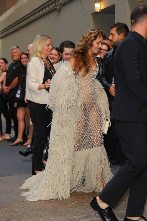 Miley Cyrus showcasing fashionable mesh gown with fringe hem and matching fringed coat