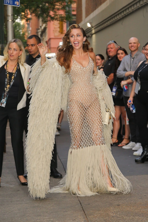 Miley Cyrus wearing transparent diamond pattern dress with cream fringe details and matching coat