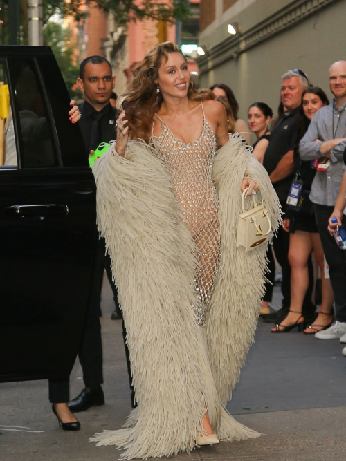 Miley Cyrus showcasing designer fringe coat over transparent dress at public appearance