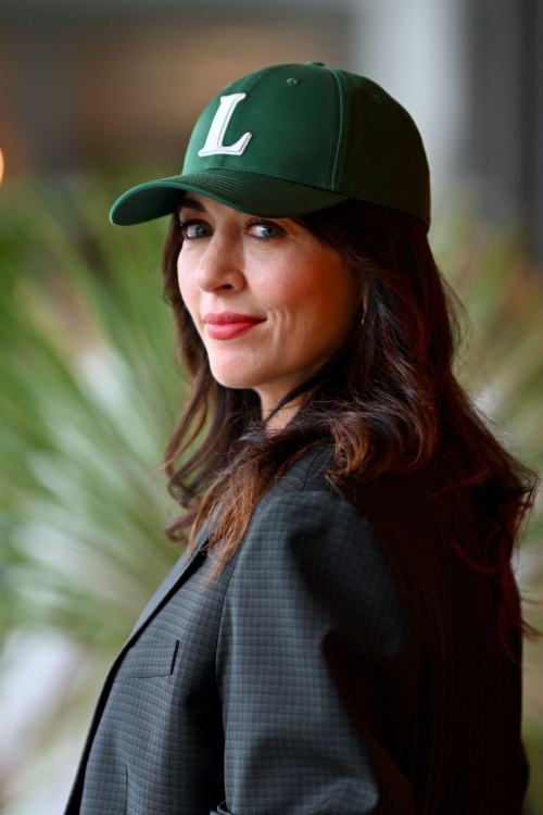 Close-up profile of Nolwenn Leroy wearing green Lacoste cap with L logo and dark blazer at Roland Garros 2025 tournament