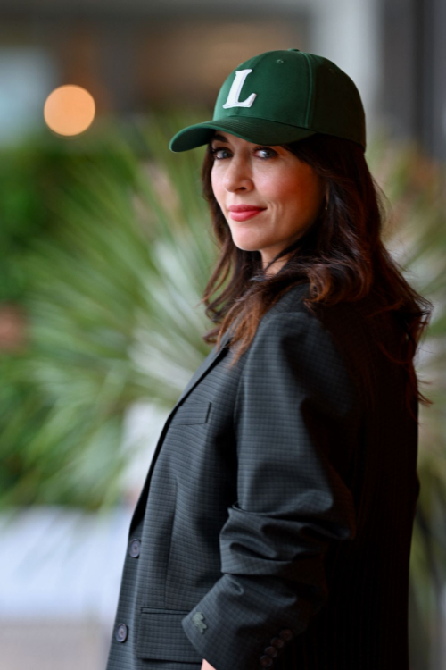 Side profile of Nolwenn Leroy with wavy hair under green Lacoste cap and dark blazer at Roland Garros French Tennis Open 2025