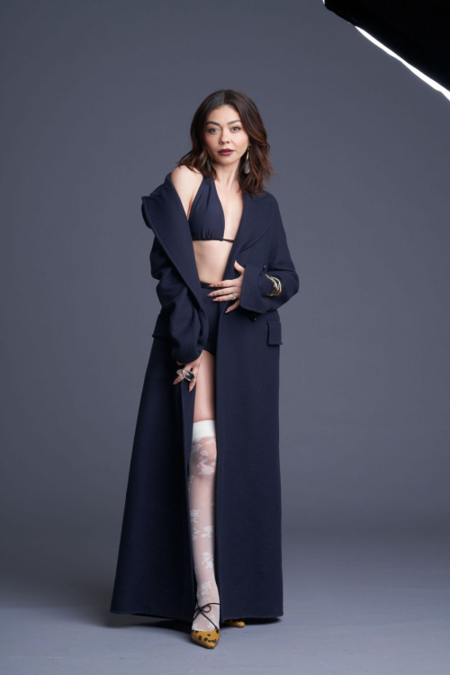 Sarah Hyland modeling navy blue floor-length coat over black bikini top with patterned stockings and gold heels for Paper Magazine high-fashion editorial June 2025