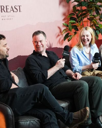 Dakota Fanning wearing high-waisted beige trousers and light blue shirt.