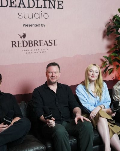 Dakota Fanning in relaxed light blue button-up and beige trousers.