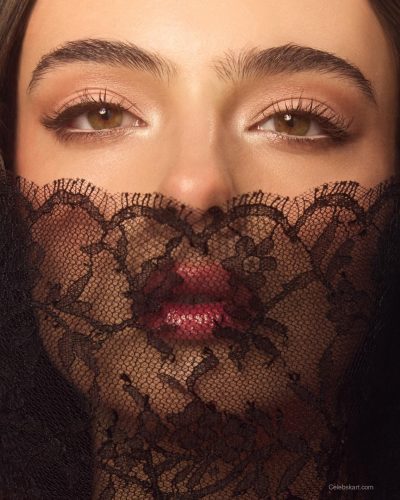 Deva Cassel in black satin cape with subtle shine.