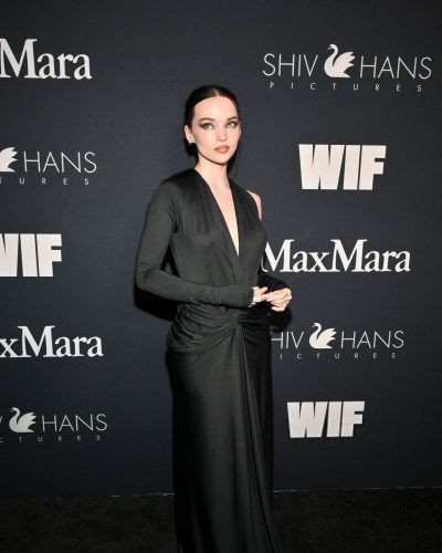 Dove Cameron wearing a form-fitting black dress with a twist design.