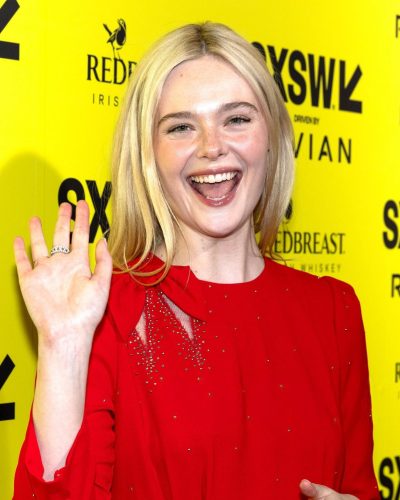 Dakota Fanning in a white belted dress complemented by black boots