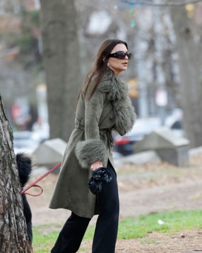 Emily Ratajkowski black trousers and green coat with fur details.