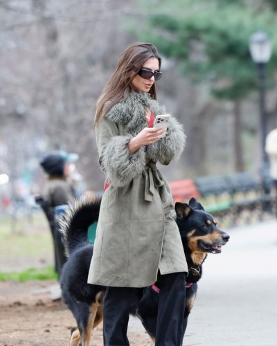 Emily Ratajkowski green trench coat with black pants and stylish loafers.