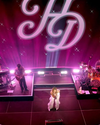 Hilary Duff in casual attire with vibrant stage lighting.