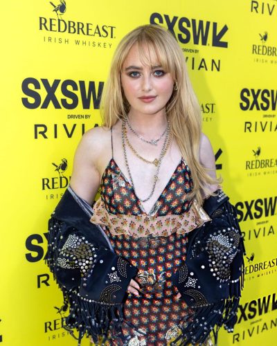 Kathryn Newton embellished suede jacket over floral dress.