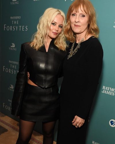 Millie Gibson in a black leather dress with stylish pointed shoes