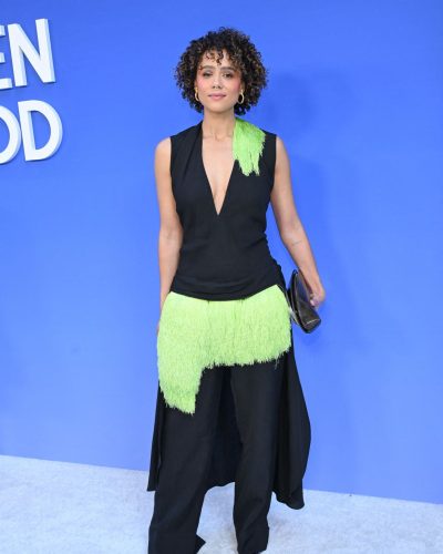 Nathalie Emmanuel in black V-neck top and fringed lime green trousers