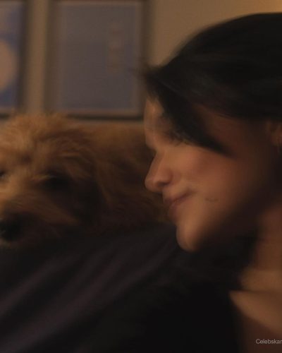 Rachel Zegler in light grey tank top and playful dog moment.