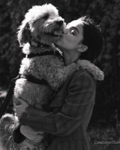 Rachel Zegler in light grey tank top and denim shorts.
