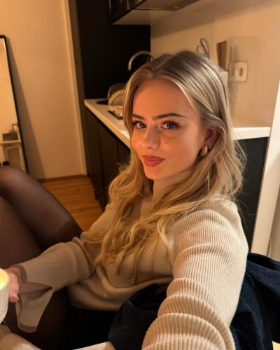 Sara Crumbleleg in a cozy beige sweater and stylish shorts