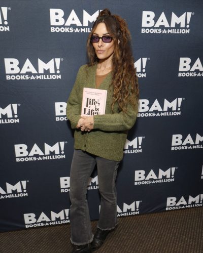 Sarah Shahi wearing a relaxed-fit gray cardigan and brown top.
