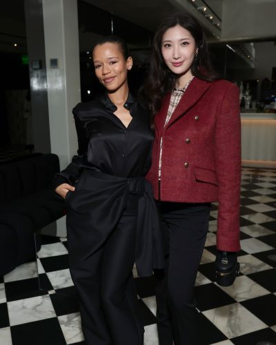 Taylor Russell wearing black satin shirt and elegant high-waisted pants.