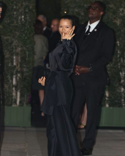 Taylor Russell in black satin shirt and dramatic flowy pants.
