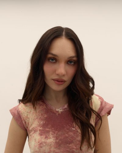 Uma Thurman in vintage logo red sweater and brown trousers.