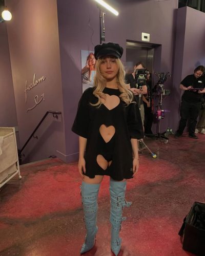 Victoria Pedretti black dress featuring heart cutouts and knee-high blue boots