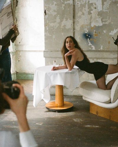 Alana Haim wearing a black form-fitting dress with fishnet stockings.