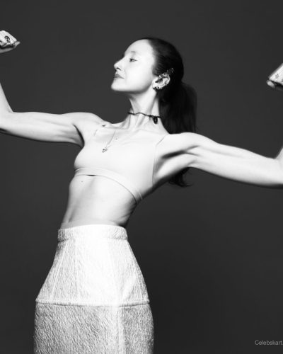 Andrea Riseborough in black shirt with statement text and white skirt