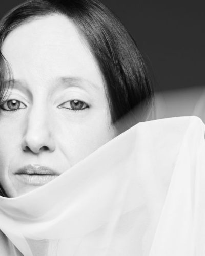 Andrea Riseborough wearing black graphic t-shirt and chic white skirt