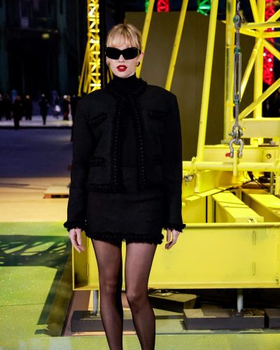 ANGELE in fitted black jacket and short black skirt