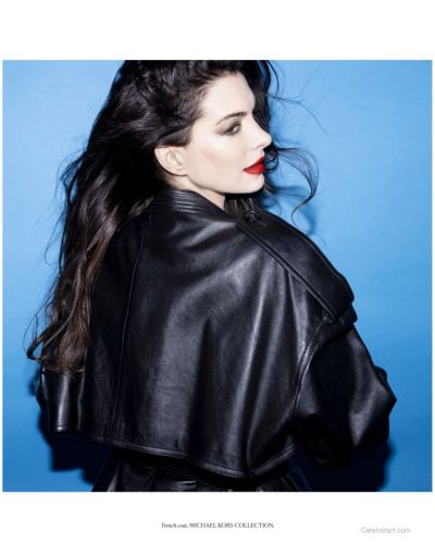 Anne Hathaway wearing chic black waistcoat against blue background.