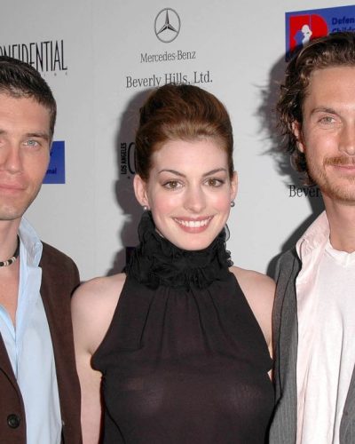 Anne Hathaway form-fitting black top with ruffles and slacks