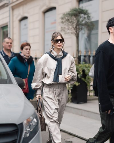 Barbara Palvin with large sunglasses and beige wide-leg trousers.