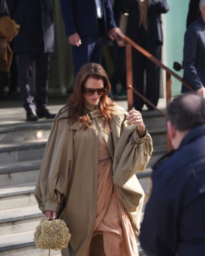 Brooke Shields dressed in light tan dress with olive green cape.