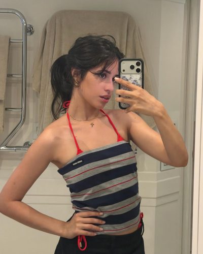 Camila Cabello in a red bikini against a palm tree.