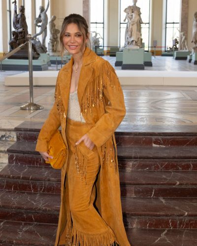 Carla Pereyra styled in flowing fringed skirt and mustard coat