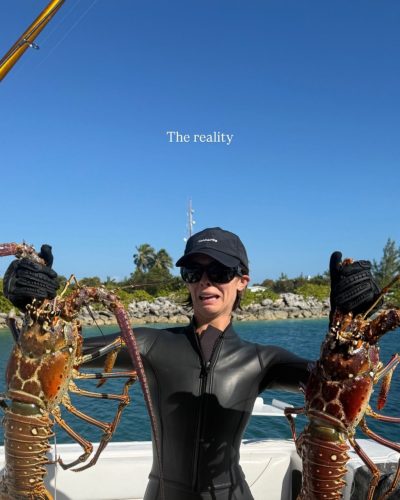 Carmella Rose in stylish black swimwear with water droplets.