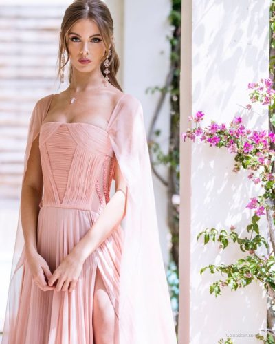 Carmella Rose in trendy black swimsuit against tranquil water.