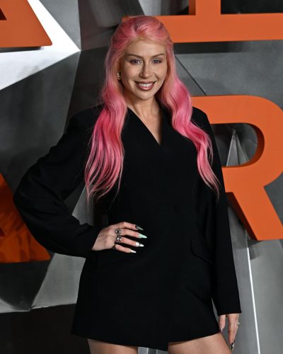 CC Clarke wearing a chic black mini skirt and tailored blazer.