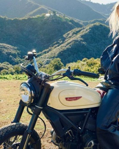 Charlize Theron in black leather jacket, white tee, and sleek pants.