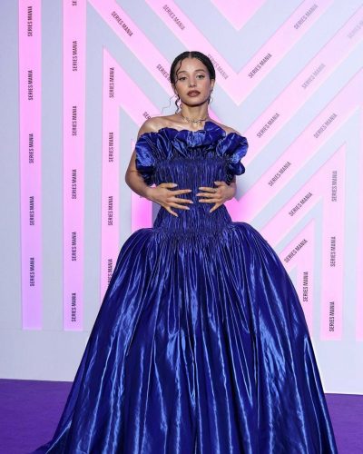 Chase Infiniti wearing glossy blue gown with ruched details.