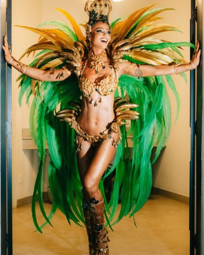 Cintia Dicker dressed in a bold gold gown with lush green feathers