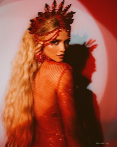 Cintia Dicker wearing a vibrant feather headpiece and golden bodysuit