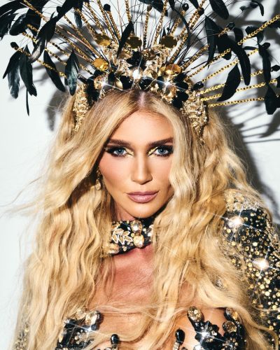 Cintia Dicker wearing a golden bodysuit with striking green feathers