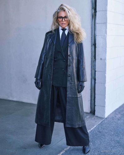 Claudia Black in black tailored blazer and wide-leg pants.