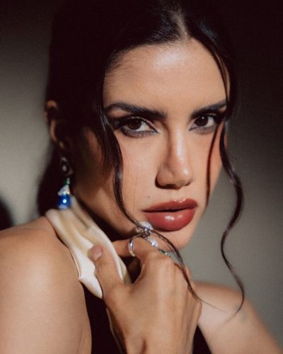 Claudia Coria adorned with colorful jewelry and black attire.