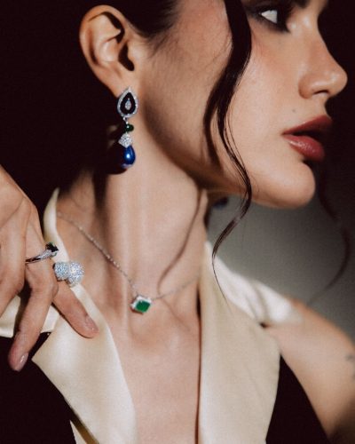 Claudia Coria in a dark gown with vibrant green jewels.