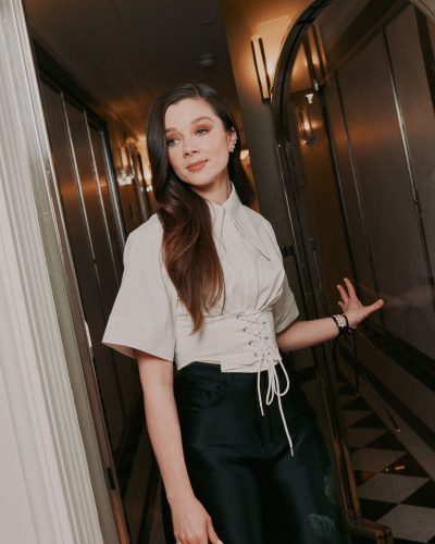 Claudia Jessie in stylish light gray top with black pants.